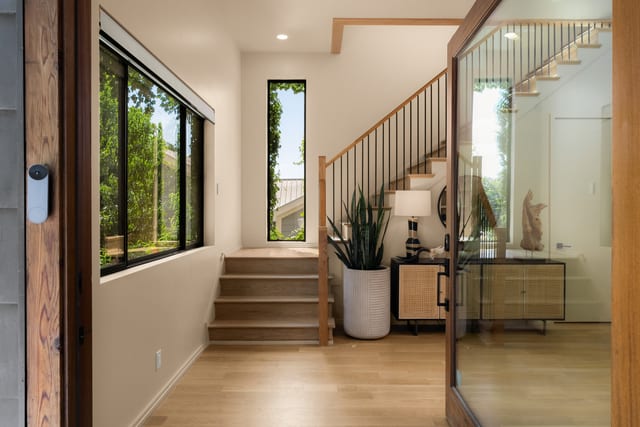 Open glass entry door leading into the bright foyer and white oak stair hall.